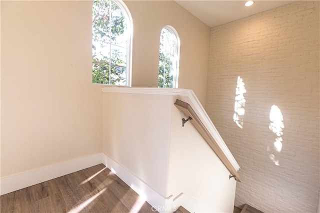 stairway with baseboards, wood finished floors, and brick wall