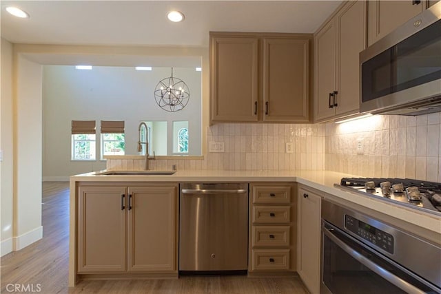 kitchen with light countertops, a sink, stainless steel appliances, and an inviting chandelier