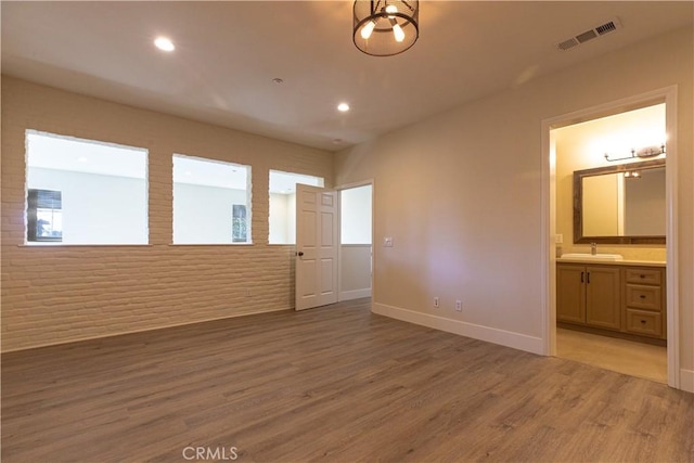 unfurnished bedroom featuring recessed lighting, a sink, connected bathroom, light wood-style floors, and visible vents