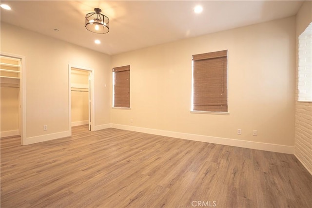 unfurnished bedroom featuring baseboards, recessed lighting, wood finished floors, and a spacious closet