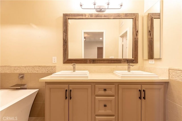 full bath with double vanity, a sink, tile walls, and a freestanding bath