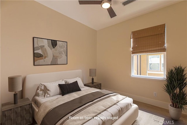 bedroom featuring a ceiling fan, wood finished floors, baseboards, and visible vents