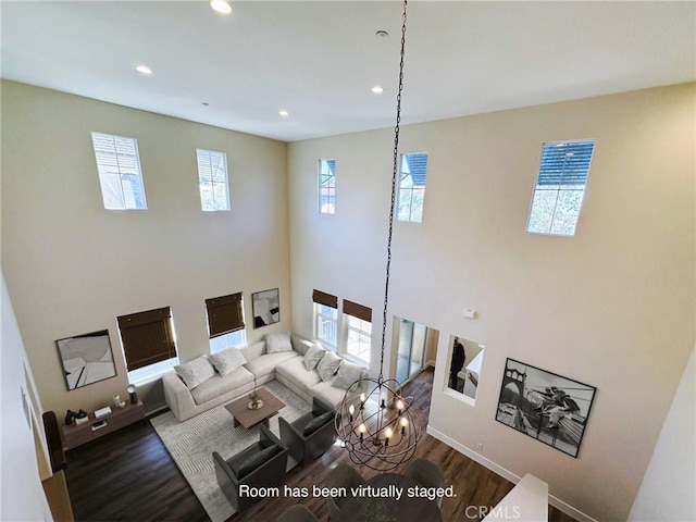 living room with recessed lighting, a towering ceiling, and wood finished floors