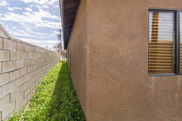 view of side of home with fence and stucco siding