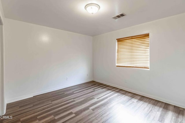 unfurnished room featuring visible vents, baseboards, and wood finished floors