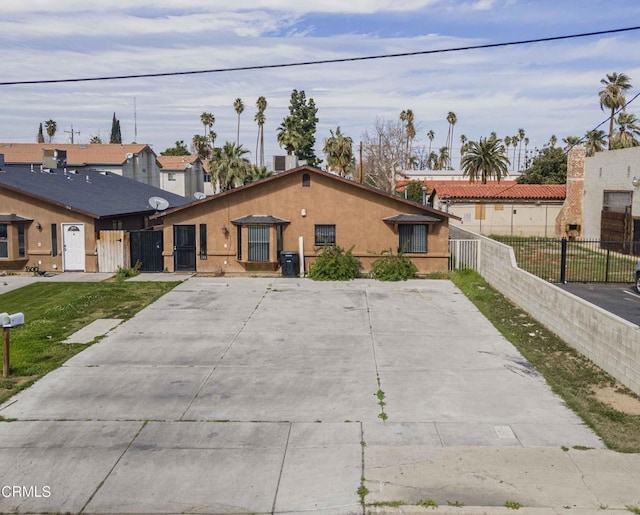 view of front of home featuring a front yard, fence, and stucco siding