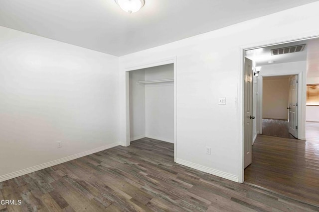 unfurnished bedroom with a closet, visible vents, baseboards, and wood finished floors