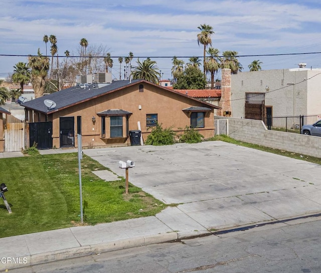 view of front of property with fence, a front lawn, and stucco siding