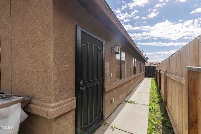 view of side of property with a fenced backyard and stucco siding