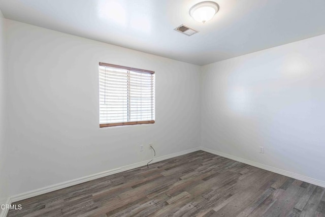 unfurnished room with wood finished floors, visible vents, and baseboards