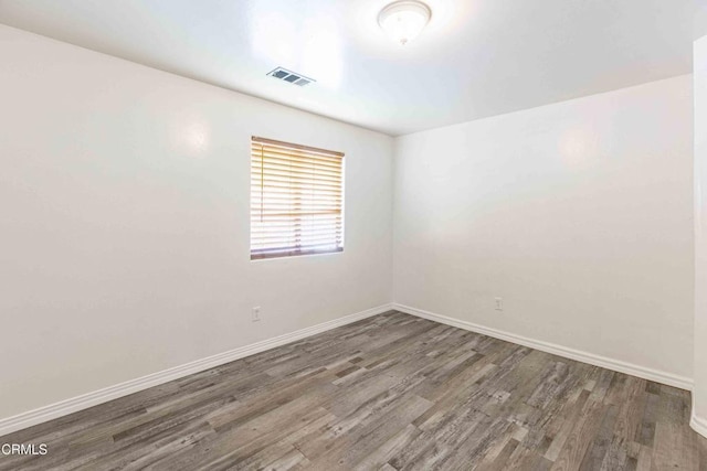 spare room featuring baseboards, visible vents, and wood finished floors