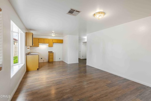 unfurnished living room with dark wood-type flooring, visible vents, and baseboards