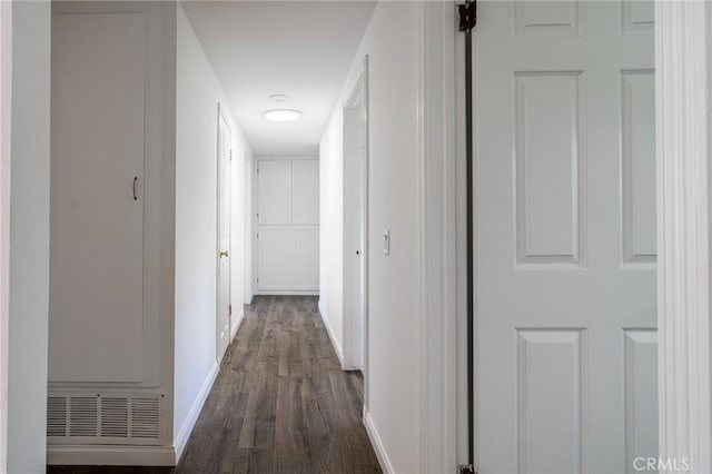 hallway featuring baseboards and dark wood-type flooring