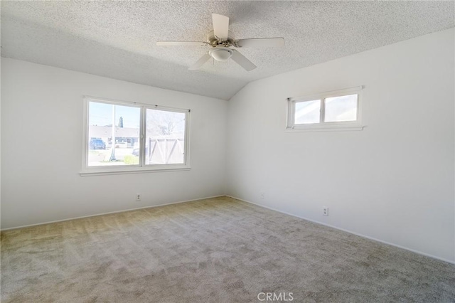 empty room featuring a textured ceiling, carpet floors, vaulted ceiling, and ceiling fan