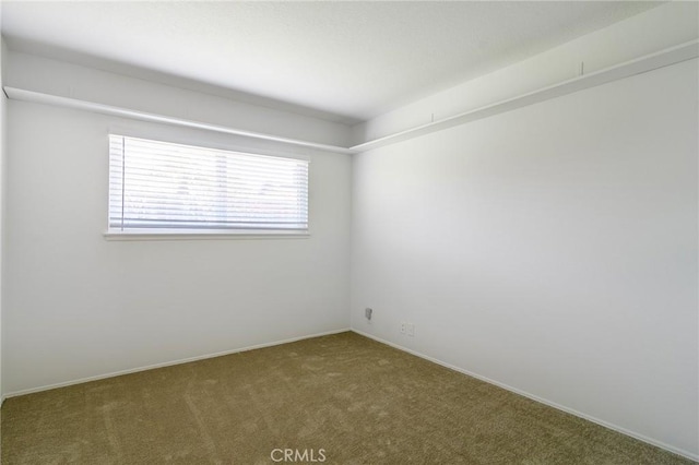 carpeted empty room featuring baseboards