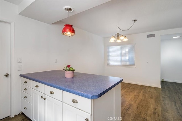 kitchen featuring a peninsula, dark wood-type flooring, dark countertops, and visible vents