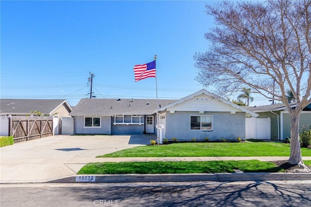 single story home with stucco siding, fence, concrete driveway, and a front yard