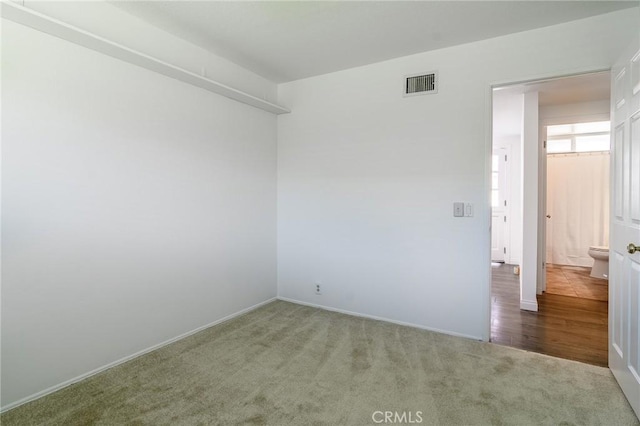 carpeted empty room featuring baseboards and visible vents