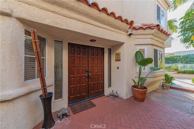 property entrance with a tiled roof and stucco siding