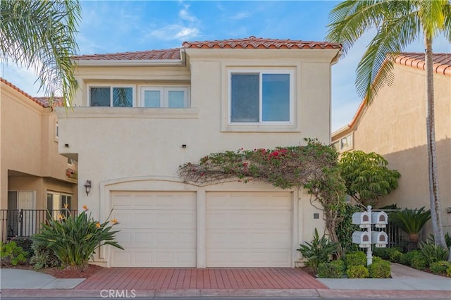 mediterranean / spanish house featuring stucco siding, decorative driveway, an attached garage, and a tile roof