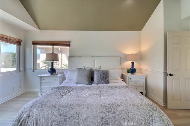 bedroom featuring lofted ceiling, light wood-style floors, and baseboards