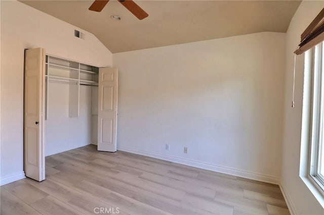 unfurnished bedroom with a closet, multiple windows, light wood-style floors, and lofted ceiling