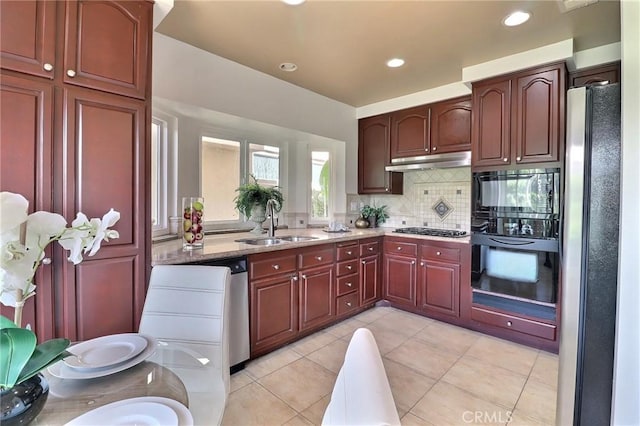 kitchen featuring backsplash, under cabinet range hood, light stone counters, black appliances, and a sink