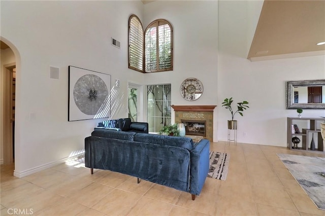 living room featuring a high ceiling, arched walkways, visible vents, and a high end fireplace