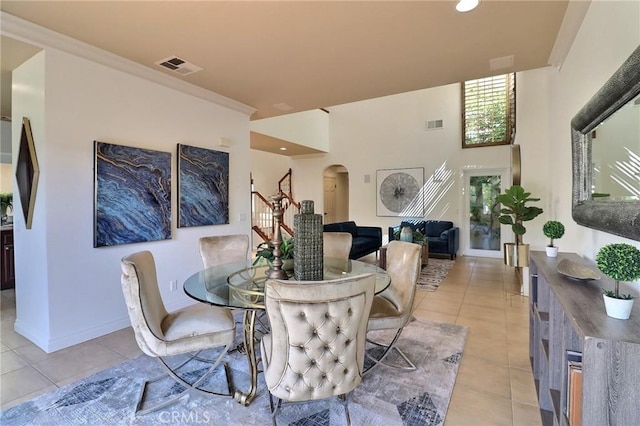 dining area featuring stairway, light tile patterned floors, visible vents, baseboards, and arched walkways