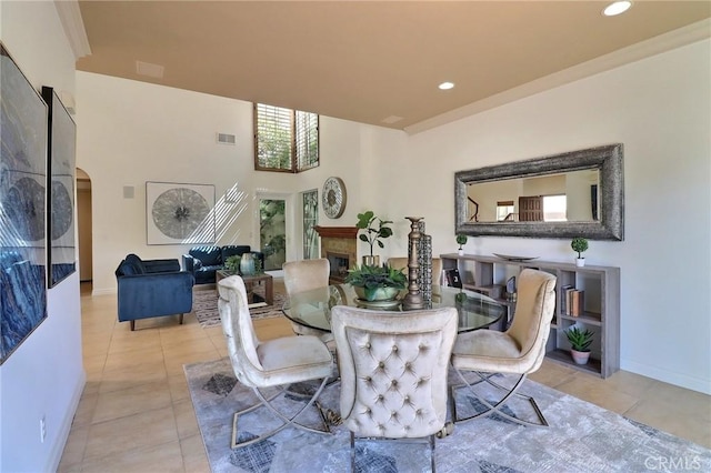 dining area featuring tile patterned floors, recessed lighting, arched walkways, a fireplace, and baseboards