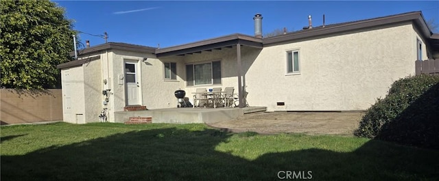 back of house featuring stucco siding, a patio area, fence, and a yard