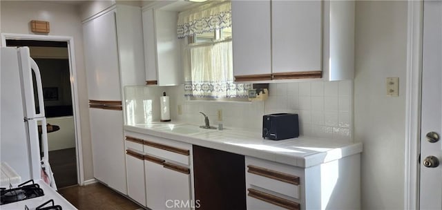 kitchen with tile counters, freestanding refrigerator, white cabinets, and tasteful backsplash