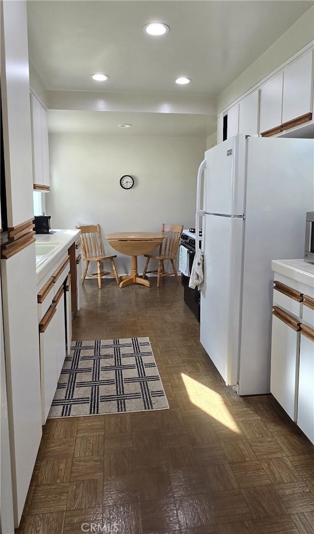 kitchen with recessed lighting, light countertops, gas stove, freestanding refrigerator, and white cabinetry