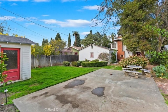 view of yard featuring a patio area, fence, and an outdoor structure