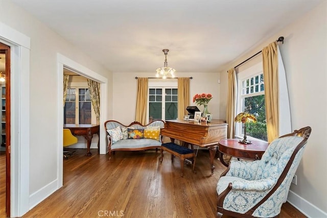 living area with an inviting chandelier, baseboards, and wood finished floors