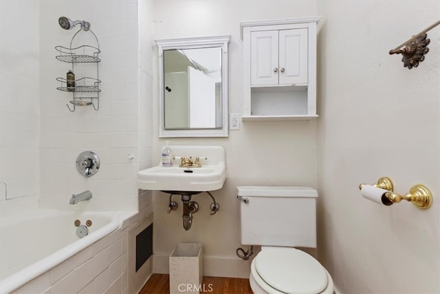 bathroom featuring baseboards, shower / bath combination, toilet, and wood finished floors