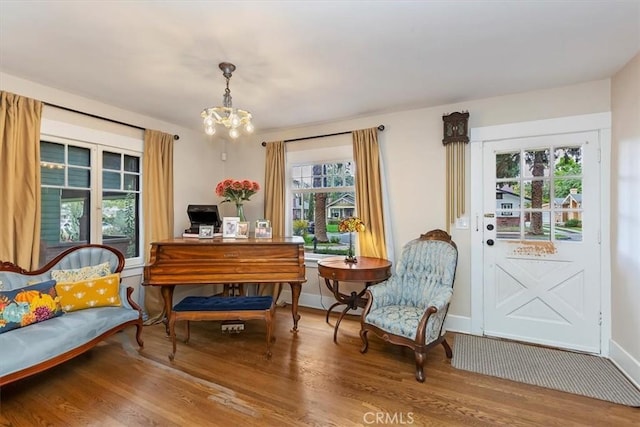 sitting room with baseboards, a chandelier, and wood finished floors