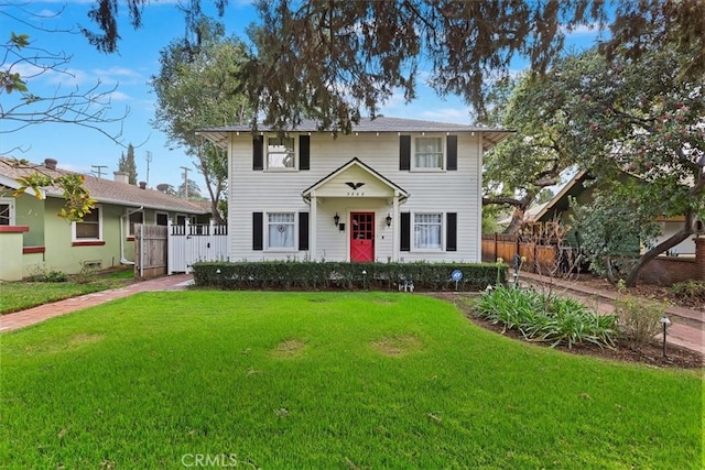 colonial inspired home with fence and a front lawn