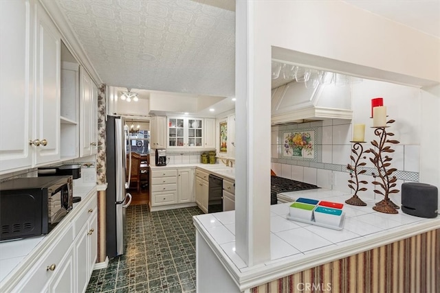 kitchen featuring tile countertops, black appliances, tasteful backsplash, and white cabinets