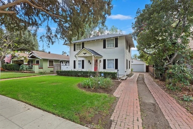 view of front of house with an outbuilding, a detached garage, and a front yard