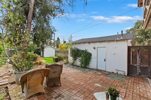 view of patio featuring an outbuilding, a gate, and fence