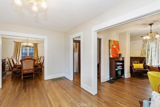 dining area with baseboards, a healthy amount of sunlight, wood finished floors, and a notable chandelier