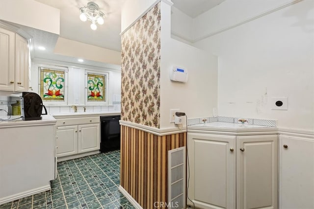 kitchen with white cabinets, light countertops, dishwasher, and wainscoting