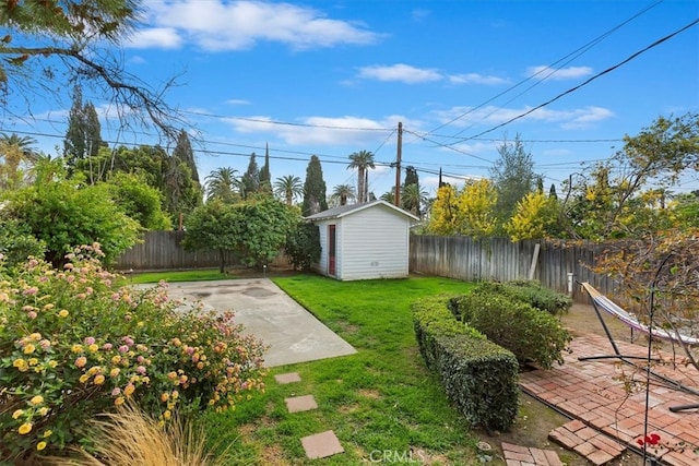 view of yard with an outbuilding, a patio, a storage unit, and a fenced backyard