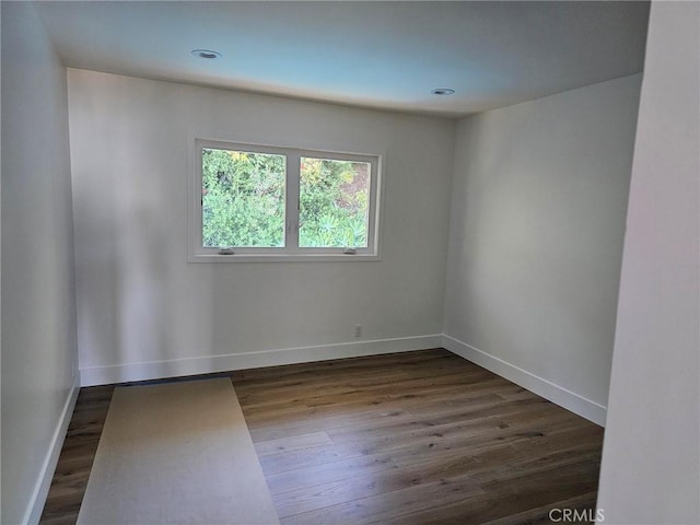 empty room featuring dark wood-type flooring, recessed lighting, and baseboards