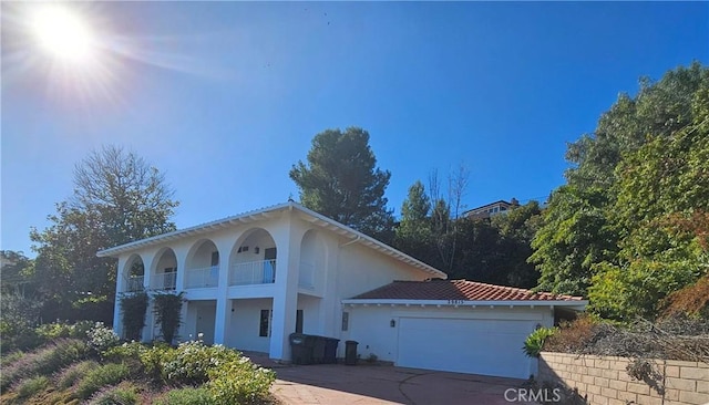 mediterranean / spanish-style house with a garage, concrete driveway, a balcony, and stucco siding