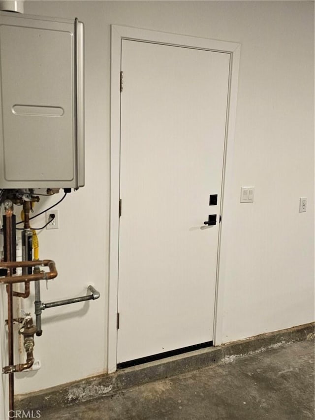 doorway featuring water heater and unfinished concrete floors