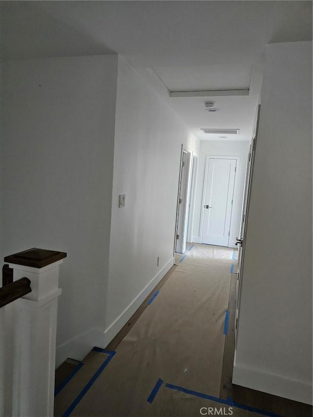 hall with attic access, baseboards, and an upstairs landing