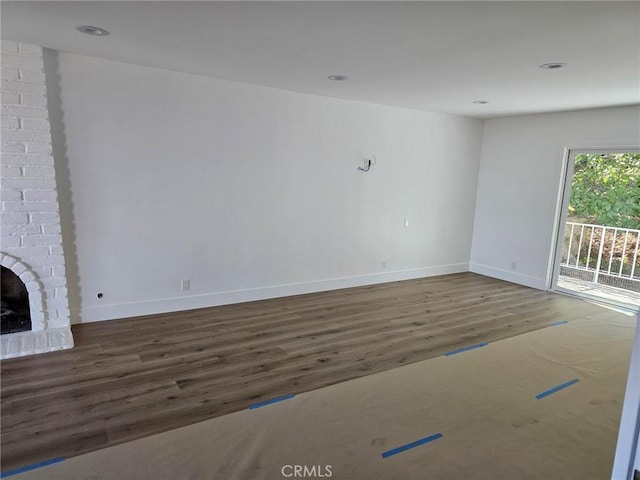 unfurnished living room with recessed lighting, a fireplace, wood finished floors, and baseboards