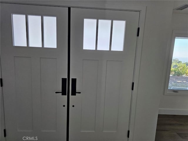 entryway with dark wood-style floors, visible vents, and baseboards